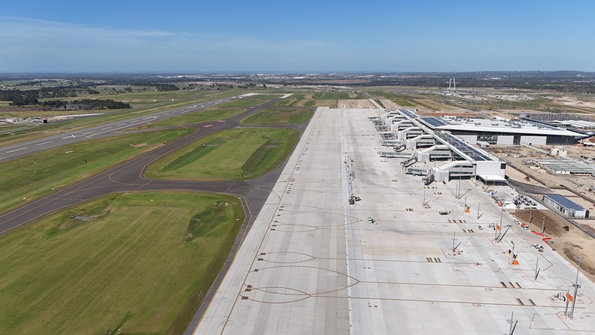 Aerial view of an airport apron with yellow aircraft stand lead-in markings beside a taxiway