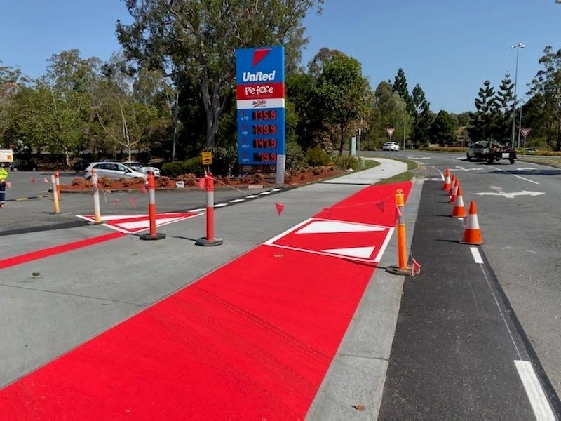 Red high-visibility safety surfacing and white give-way markings at a United petrol station forecourt
